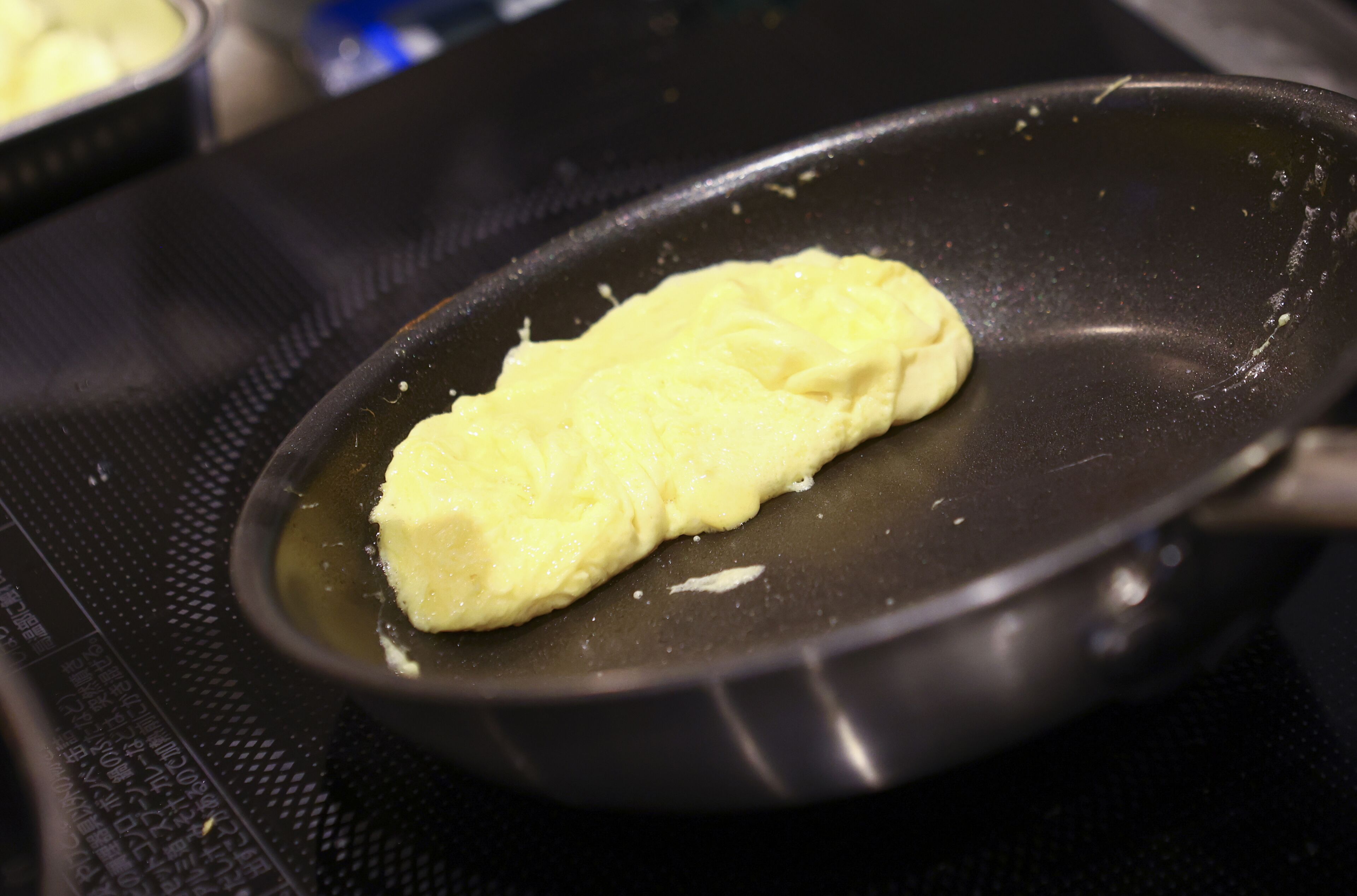 Una sartén antiadherente sobre una hornilla, con un alimento cocinándose.