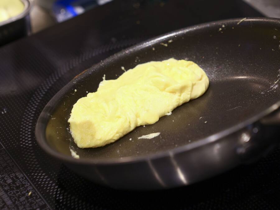 Una sartén antiadherente sobre una hornilla, con un alimento cocinándose.