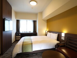 Une chambre d’hôtel avec un lit, un bureau, une chaise, une télévision et une fenêtre avec des rideaux.