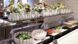 A buffet area with various food items and decorative flowers on display. - Dormy Inn Ikebukuro Hot Springs (Tokyo)