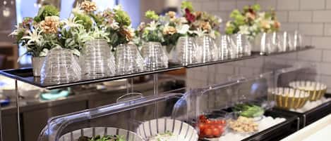A buffet area with various food items and decorative flowers on display.