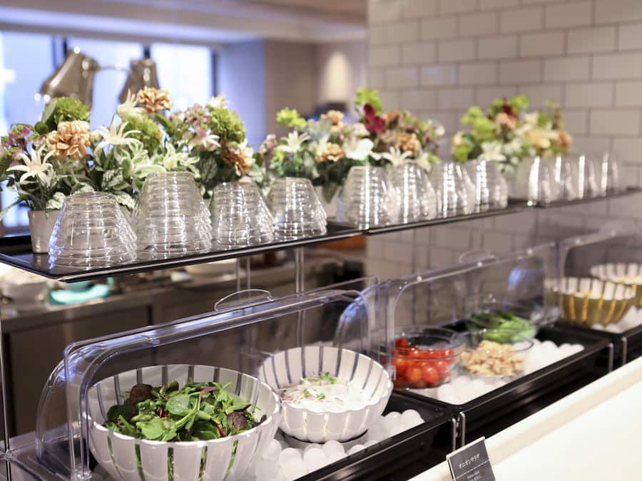 A buffet area with various food items and decorative flowers on display.