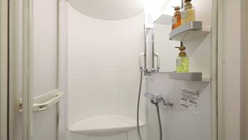 A shower with a white door, a glass shower door, and a shelf with toiletries.