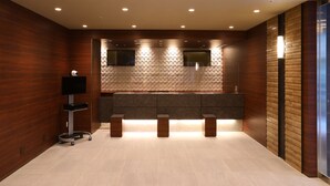 A modern bathroom with a wooden wall, a tiled floor, a large mirror, and a built-in sink. - Dormy Inn Ikebukuro Hot Springs (Tokyo)