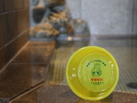 A yellow object with Japanese text and a cartoon character on a tiled floor.
