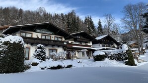 Un hôtel de style alpin traditionnel, doté de nombreux balcons et entouré d’un paysage enneigé.