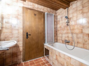 Une salle de bain avec une porte en bois, une douche et un lavabo.