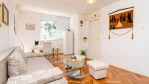 A modern living room with a sofa, a glass coffee table, and a dining area with a table and chairs. - Apartment Marina (Dubrovnik)