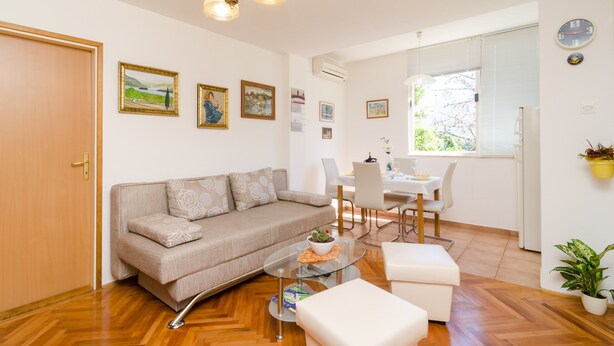 A modern living room with a sofa, coffee table, and dining area. - Apartment Marina (Dubrovnik)