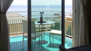 Ein Balkon mit Blick auf das Meer, ein Pool und ein Tisch mit Stühlen.