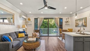 A spacious living area with a sofa, coffee table, and a view of the balcony.