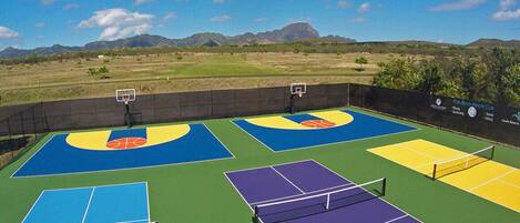 Una cancha de baloncesto al aire libre con varias canchas, una cancha de tenis y una red.