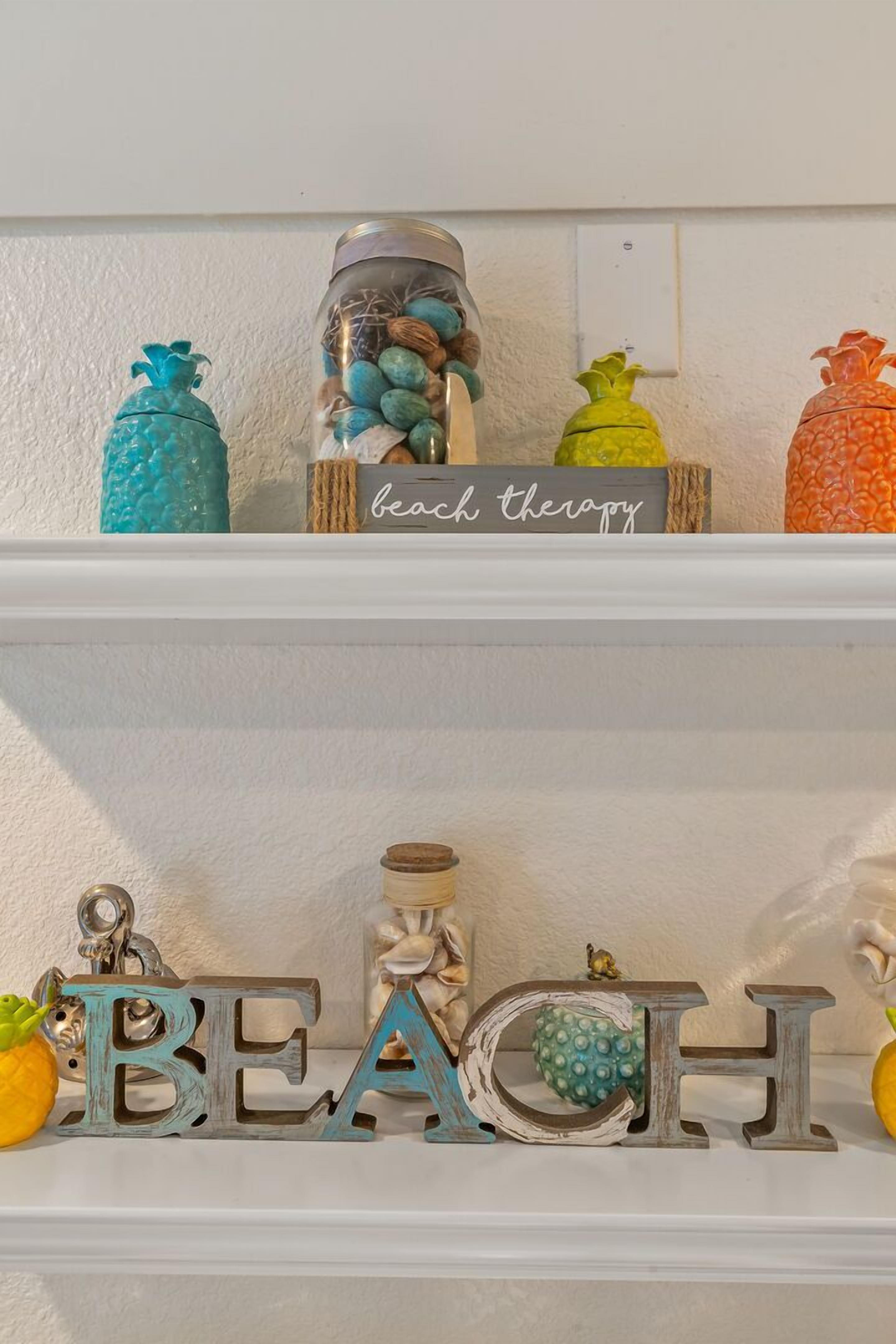 A shelf with decorative items including jars, a sign reading "beach therapy," and wooden letters spelling "BEACH."
