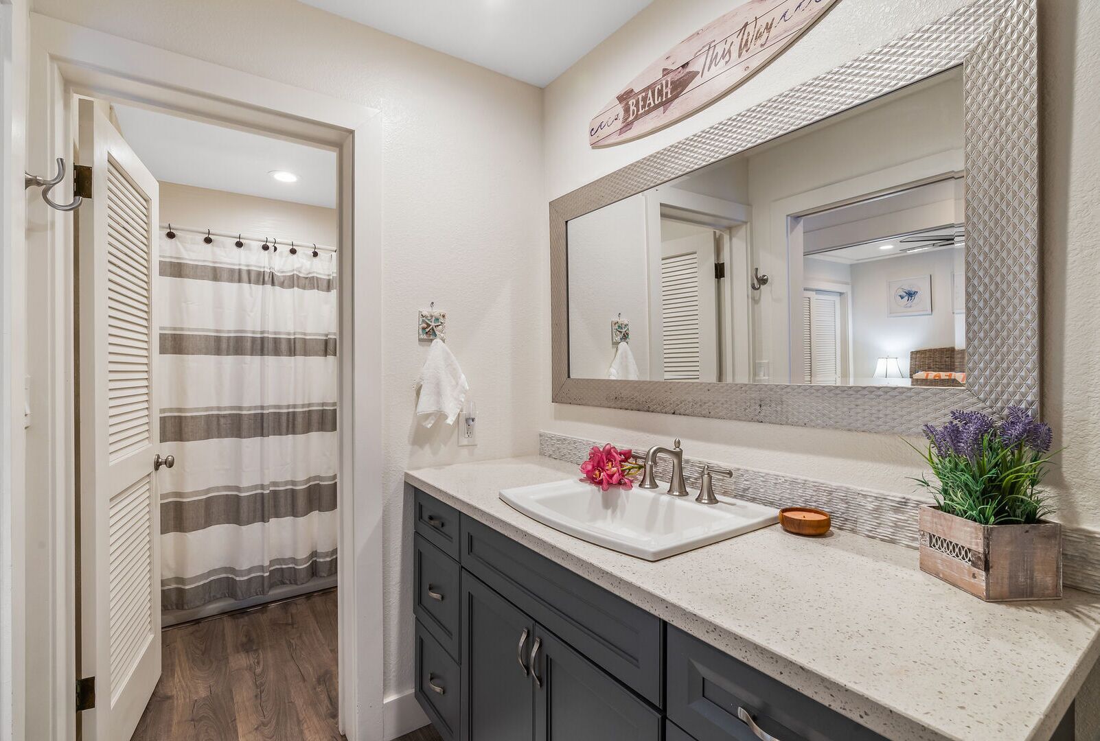A bathroom with a large mirror, a sink, and a shower curtain.