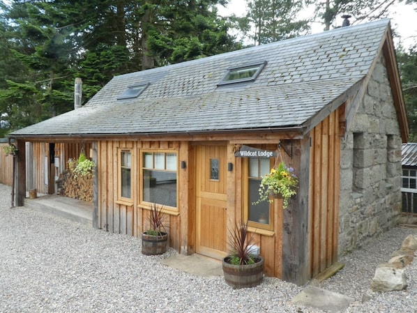 A rustic lodge with a stone exterior, wooden doors, and a gravel driveway.