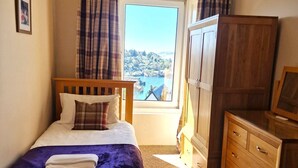 Un dormitorio con cama, cómoda, armario y ventana con vistas.