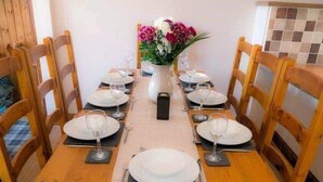 Una mesa de comedor dispuesta con platos, vasos y cubiertos, rodeada de sillas de madera.