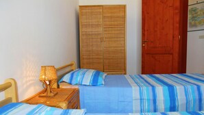 Una camera da letto con due letti, un armadio in legno e una porta in legno.