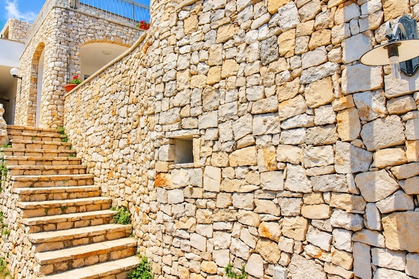 A stone staircase leading to a building with a stone wall and a small window.