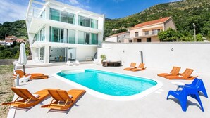Ein modernes Gebäude mit Poolbereich, inklusive Liegestühlen und Whirlpool.