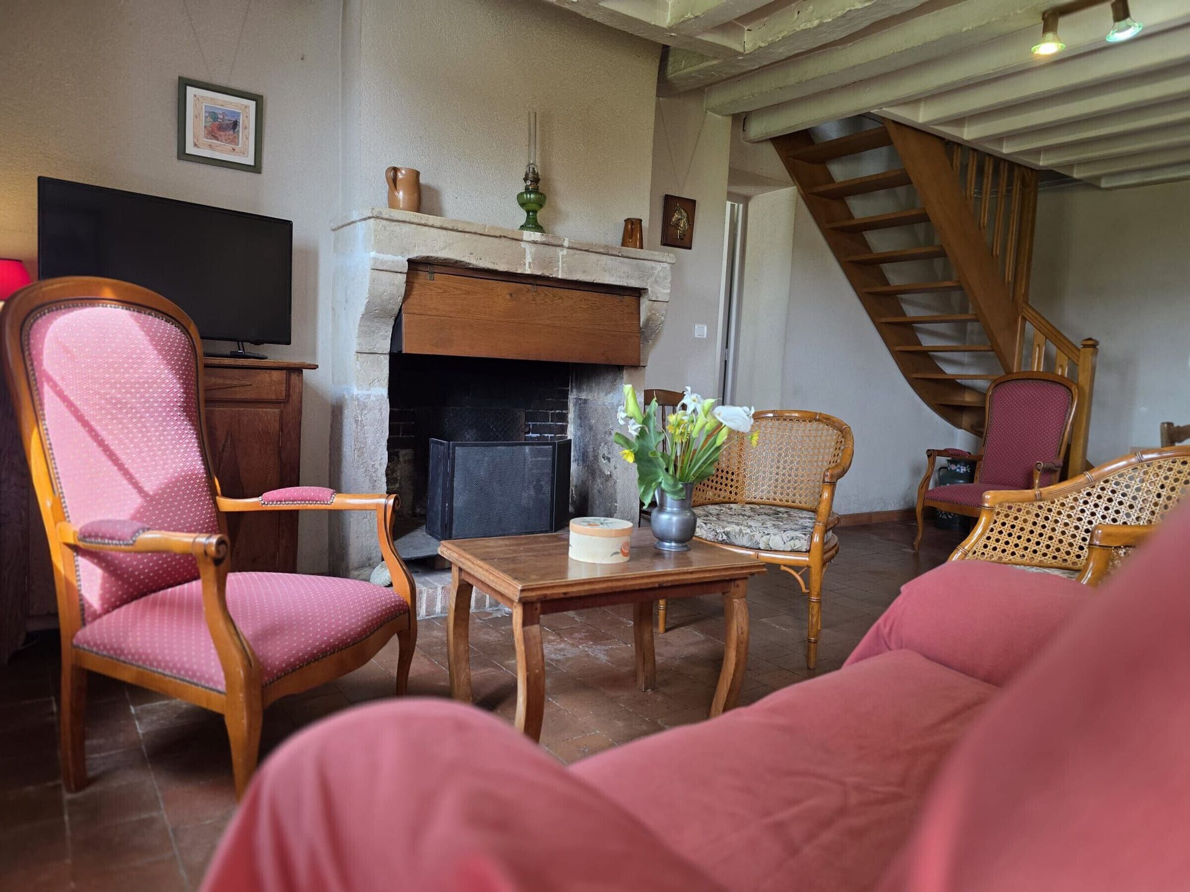 Ein Wohnzimmer mit Kamin, Holzmöbeln, einem Fernseher und einer Treppe.