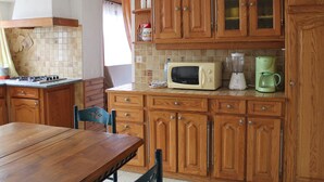 Een keuken met houten kasten, een magnetron, een koffiezetapparaat en een fornuis.