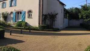 Una casa de dos pisos con camino de tierra y un pequeño jardín.