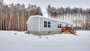 Ein eingeschossiges Mobilheim mit einer Holzterrasse und einer Rampe, die zum Eingang führt.