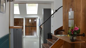 A staircase with a wooden handrail and a black metal handrail, leading to a room with a large window and a door.