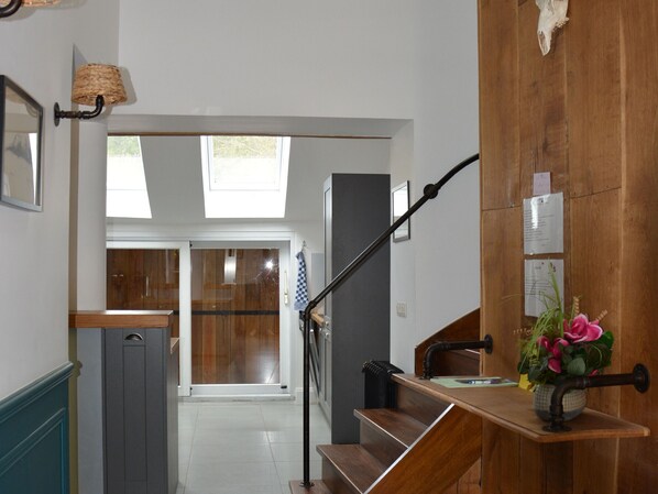 Una escalera con barandilla de madera y de metal negro, que conduce a una habitación con un ventanal y una puerta.