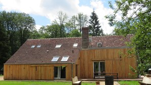 A wooden building with a sloped roof, a chimney, and a large sliding glass door.