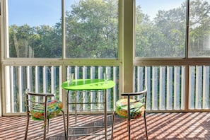 Enjoy a peaceful retreat with a view of lush greenery from the large window, featuring a small table and two chairs.