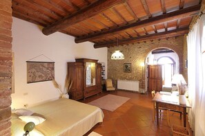 A rustic room with a bed, wooden furniture, a stone wall, and a dining area. - Chiara - Cozy Accommodations in Chianti with Private Space (Florence)