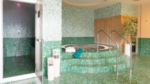 Un baño con pared de mosaicos, cerramiento de ducha de vidrio, bañera independiente y un armario de madera.