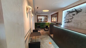 Un interior moderno con una recepción, un área de descanso y un mural en la pared.