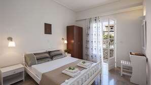 Ein ordentlich eingerichtetes Schlafzimmer mit Bett, Nachttischen, einem Kleiderschrank und einer kleinen Sitzecke.