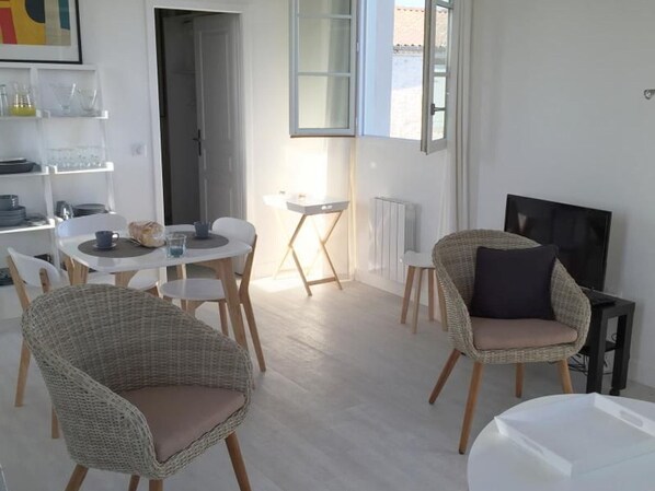 Una sala moderna con sillas de mimbre, una mesa de comedor y un televisor.