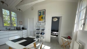 Een lichte keuken met witte kastjes, een eettafel en een hanglamp.