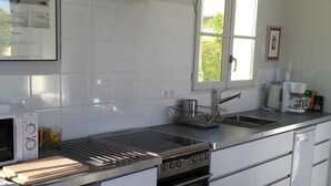 Een moderne keuken met witte kasten, een roestvrijstalen aanrecht, een inbouwoven en een koffiezetapparaat.