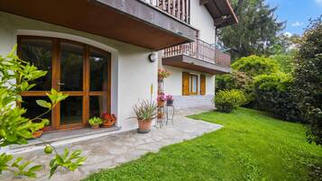 Un edificio a due piani con un balcone, piante in vaso e un vialetto in pietra che conduce all'ingresso.