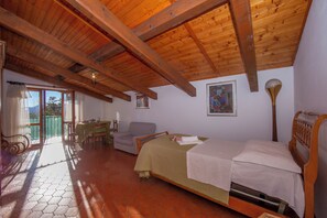 Una habitación con cama, una silla, una mesa y un balcón con vistas.