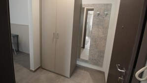 A room with a wardrobe, a shower area, and a door leading to another room.