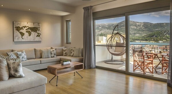 A modern living room with a sofa, coffee table, and a view of a balcony with outdoor furniture.