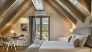 Une chambre avec un grand lit, un bureau et une chaise. Il y a une fenêtre avec des rideaux, et une vue sur l’extérieur.