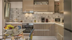 Une cuisine moderne avec une table à manger en verre, des chaises colorées et divers appareils électroménagers, notamment un four à micro-ondes et un four traditionnel.