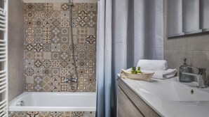 Une salle de bain avec une baignoire, une douche et un meuble-lavabo avec un miroir.
