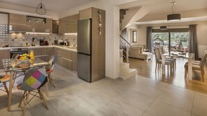 Une cuisine moderne avec un coin repas, un escalier menant à un salon et une vue sur l’extérieur.
