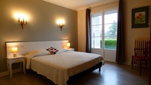 A bedroom with a large bed, bedside lamps, a window with curtains, a radiator, and a chair. - Charming Stone House in Calm Senonches - Modern Amenities & Large Garden (Senonches)