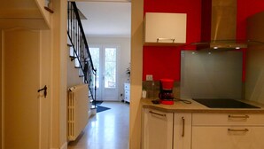 A kitchen with a red accent wall, a coffee maker, and a microwave. - Charming Stone House in Calm Senonches - Modern Amenities & Large Garden (Senonches)