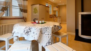 A cozy dining area with a table set for two, a radiator, a map on the wall, and a kitchen in the background. - Charming Stone House in Calm Senonches - Modern Amenities & Large Garden (Senonches)